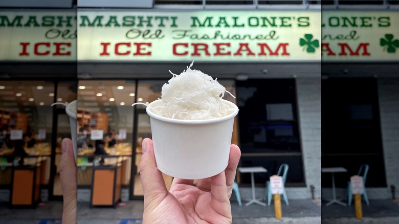 A scoop of white ice cream held out side Mashti Malone's