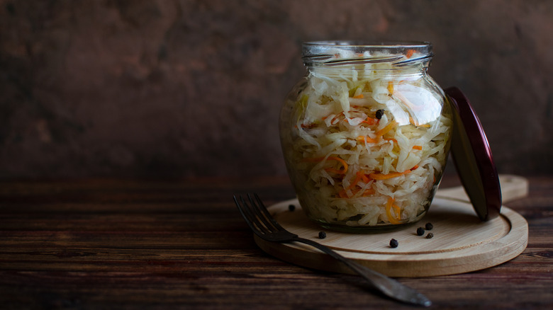 A jar of homemade sauerkraut with the lid on the side