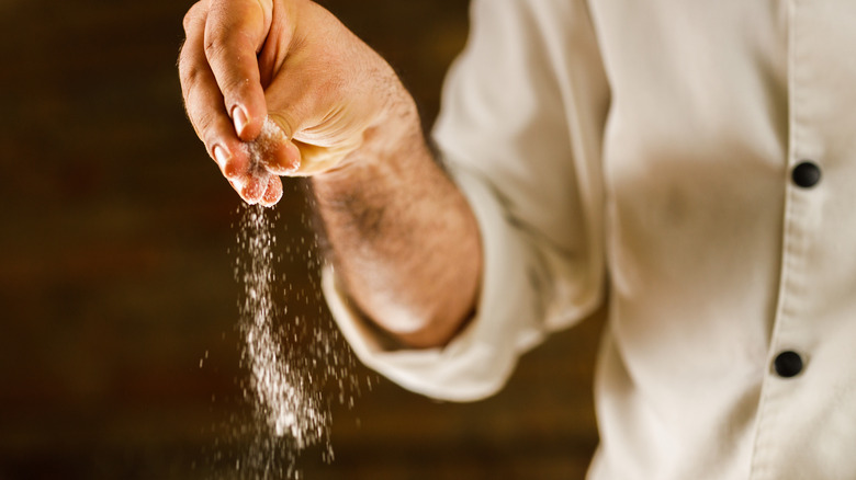 person sprinkling salt