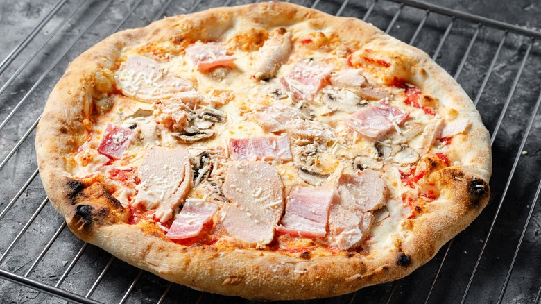 Partially cooked frozen pizza on wire rack