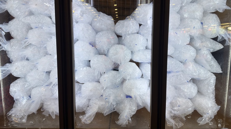 Many bags of ice in a grocery store refrigerator