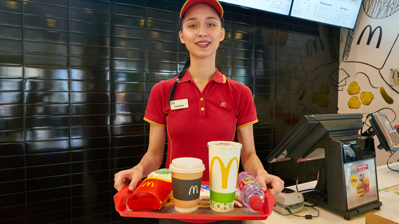 McDonald's fast food worker holding tray of food and drinks