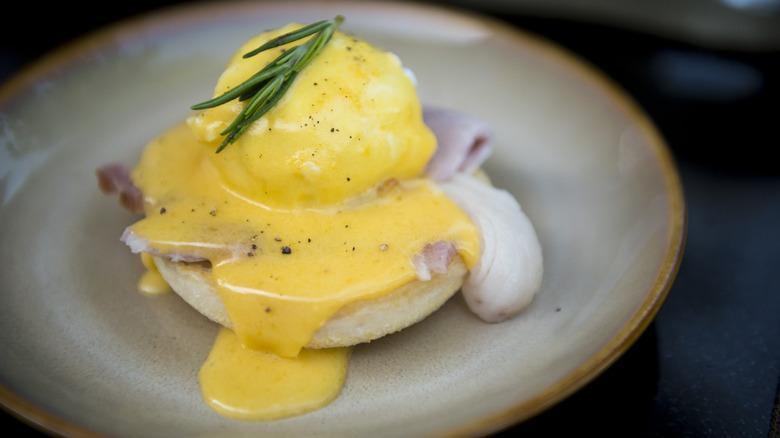 Eggs Benedict topped with Hollandaise sauce on a plate