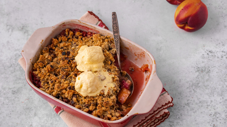Peach cobbler with a crumble topping in a tray with a spoon in it