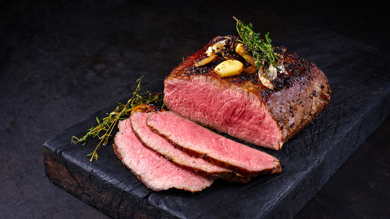 Roast beef with thyme and garlic on a cutting board