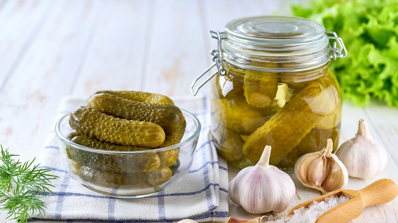 pickles in a jar and in a bowl alongside salt and garlic