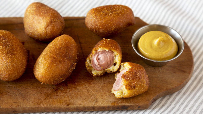 Mini corn dogs on board with mustard
