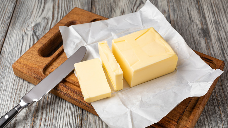 Sliced butter on wooden cutting board with wrapper