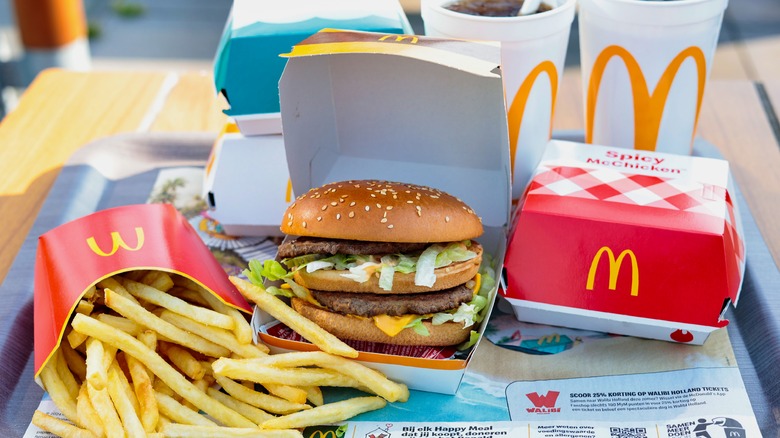 A McDonald's meal sits on a tray inside a restaurant, complete with a Big Mac, fries, and drinks