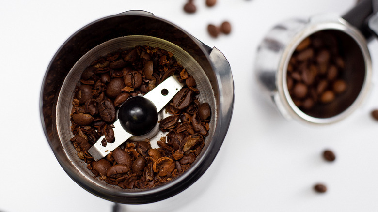 coffee grinder on white countertop with coffee beans