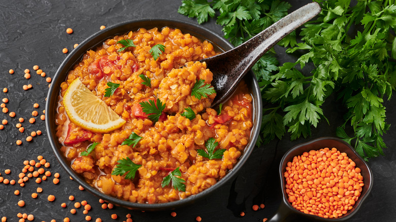 A bowl of lentil soup with parsley and lemon.
