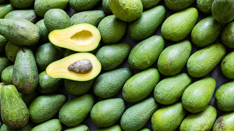 cut avocado on pile of avocados