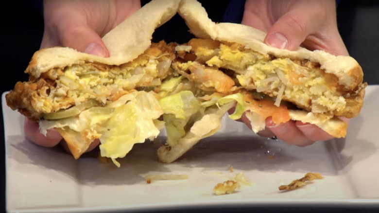 Halves of St. Paul sandwich pulled apart to show patty and vegetable toppings