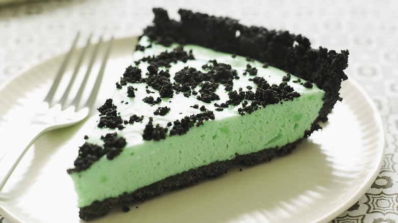 A slice of grasshopper pie on a white plate with fork
