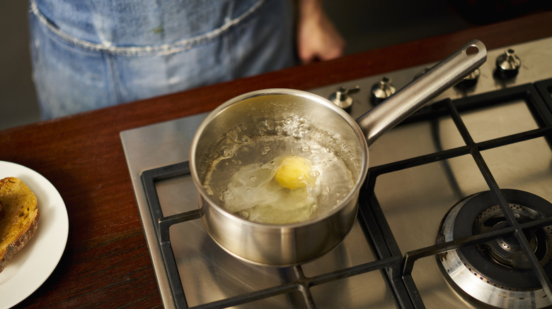 An egg poaches in a pot on a stove
