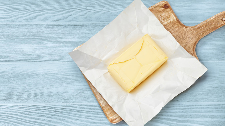 butter block with parchment paper backing on wooden cutting board