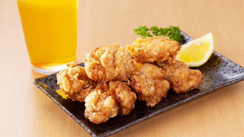 plate of karaage with a glass of beer, a lemon wedge, and fresh parsley