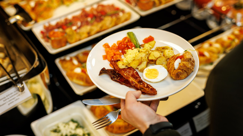 Person with a plate of breakfast foods at a buffet