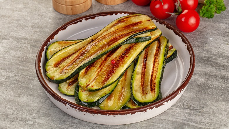 Several grilled zucchini planks in a dish