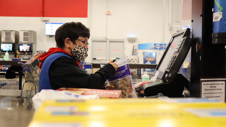 A mask-wearing customer goes through self-checkout at a Sam's Club