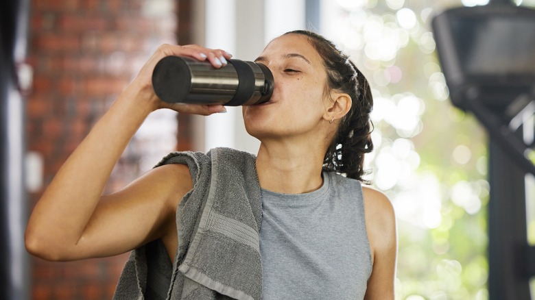 Exerciser at gym drinking from opaque bottle