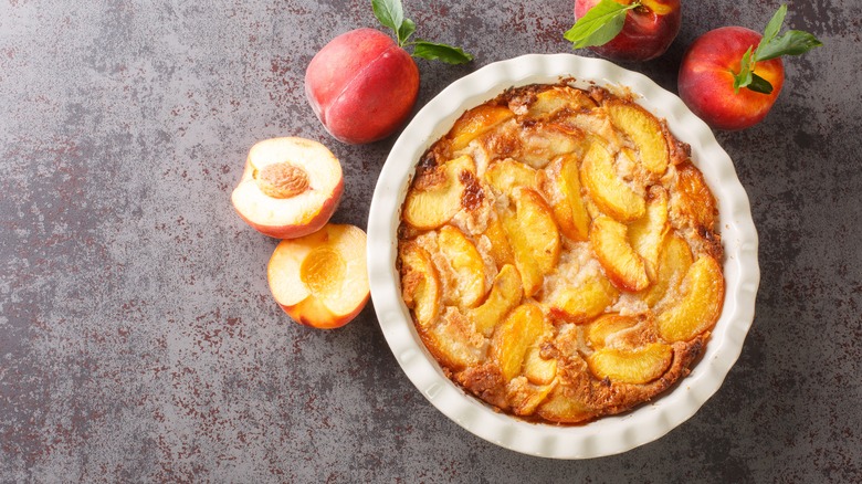 Arial shot of peach cobbler with fresh peaches on side.