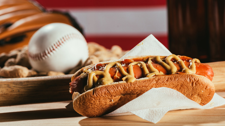 A hot dog next to a baseball ball and mitt