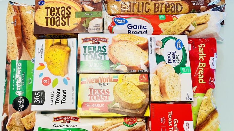 packages of different brands of garlic bread are stacked together