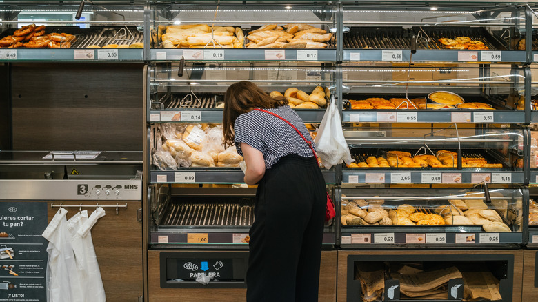 Shopper in Aldi picking up bread