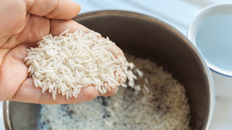 Hand rinsing white rice in pot
