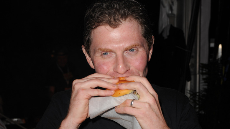 Bobby Flay eating a burger at a Rachel Ray event