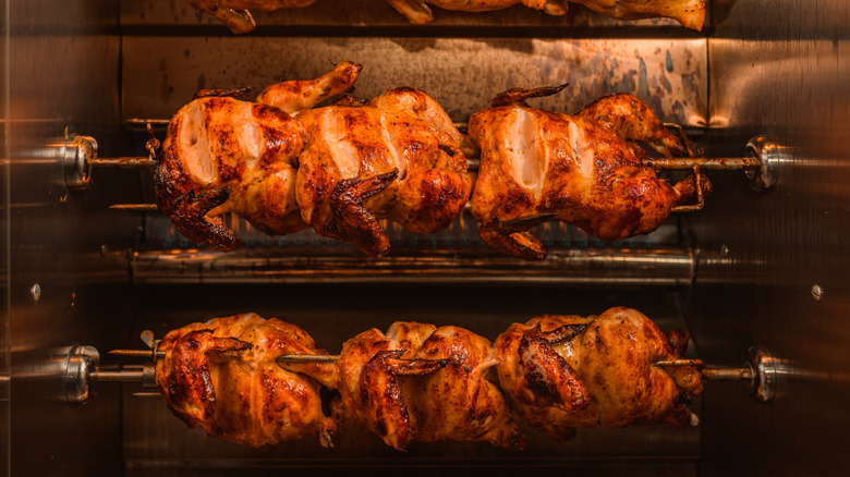 Close up of rotisserie chickens cooking on a spit