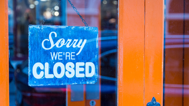Closeup on a "Sorry We're Closed" sign hanging in the door of a business