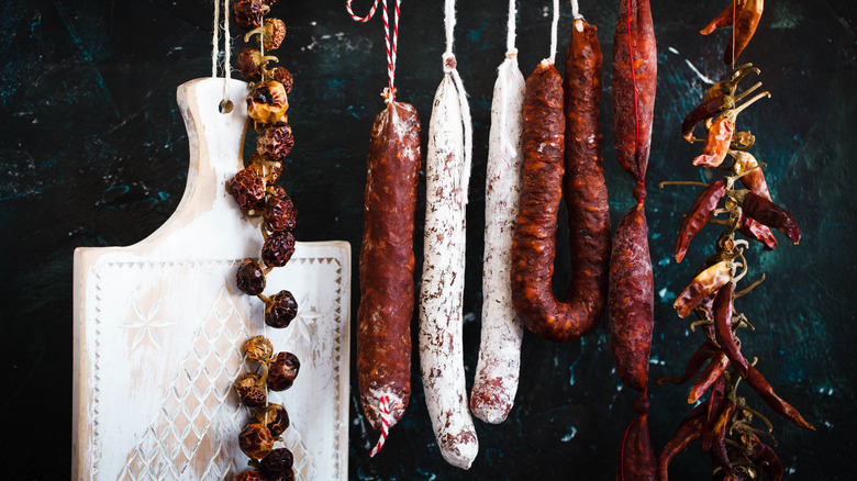Hanging salami and meat against dark background
