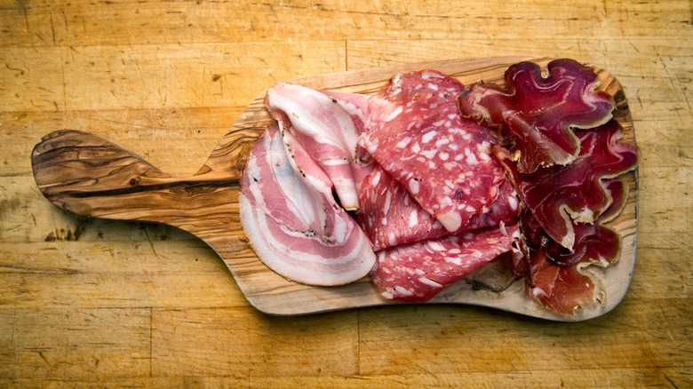 Wooden board topped with various cured meats