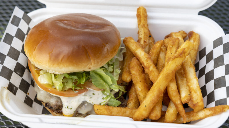 The Aloha Smash Burger in a to-go container with fries
