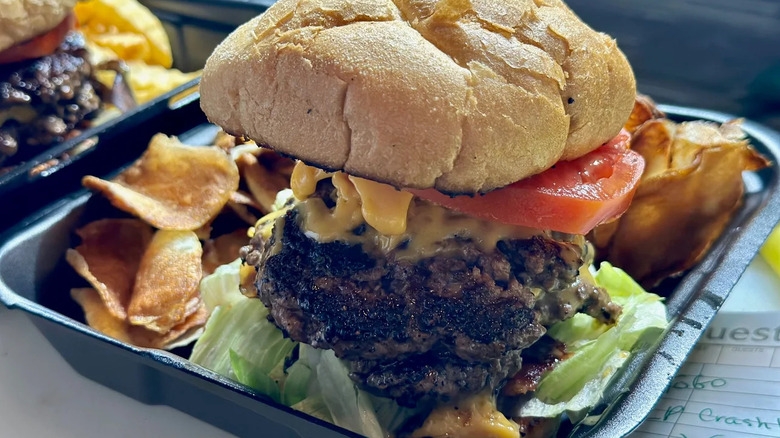 The Crashburger in a to-go container with chips
