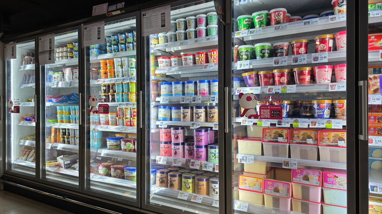 Man and woman smiling at each other at a grocery store freezer