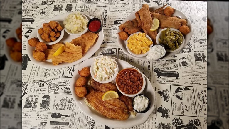 Three plates of food from PoFolks sit on a newsprint table cover
