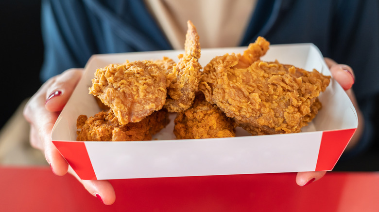 person holding fried chicken in box