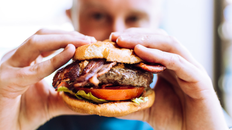 A diner holds up a hamburger, preparing to take a bite