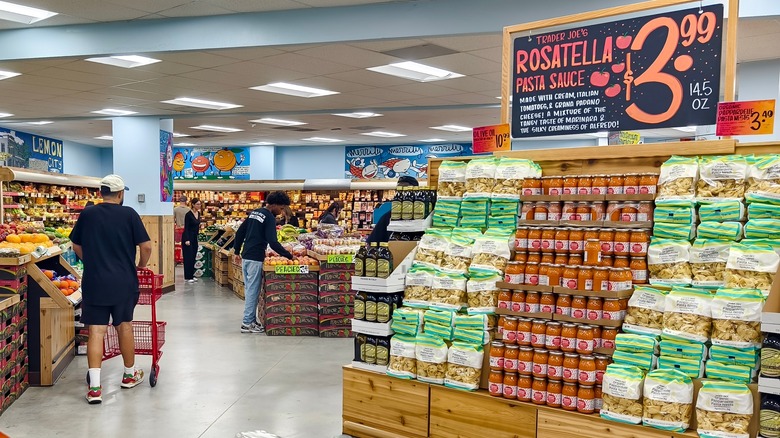 Trader Joe's shopper passing a pasta sauce advert