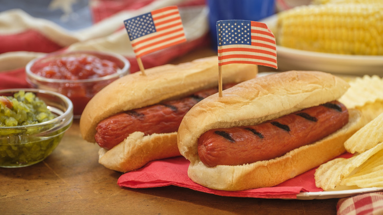 Grilled hot dogs with American flag picks in the sit on a red napkin