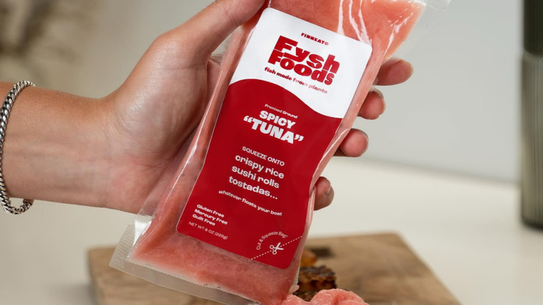 A hand holding a package of Finneato Fysh Foods spicy 