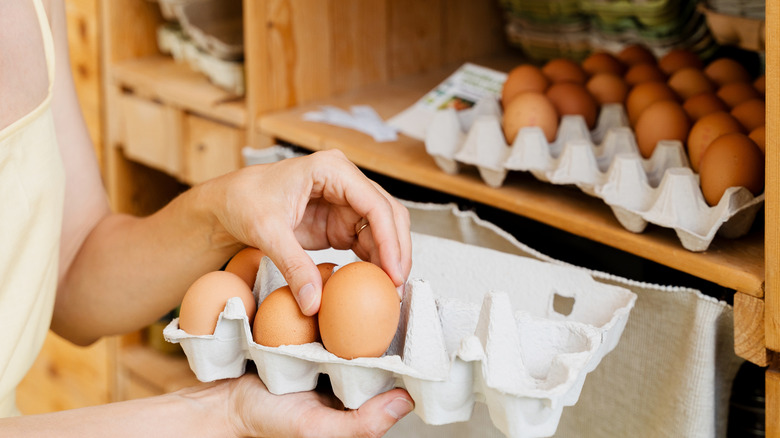 A shopper picks eggs to put into a carton to buy