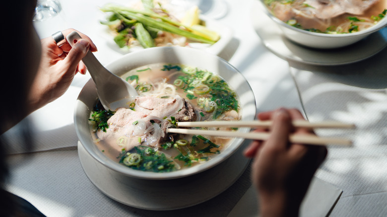 Over shoulder shot of someone eating pho
