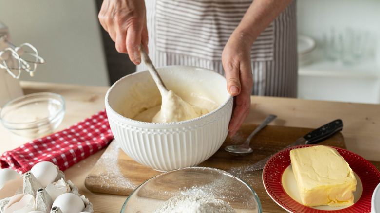 A baker mixes cake batter in a large mixing bowl