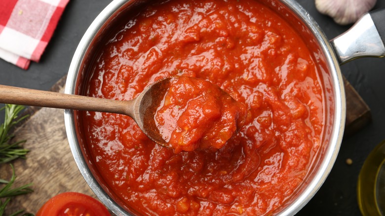 Homemade tomato sauce, in a pot, with a wooden spoon