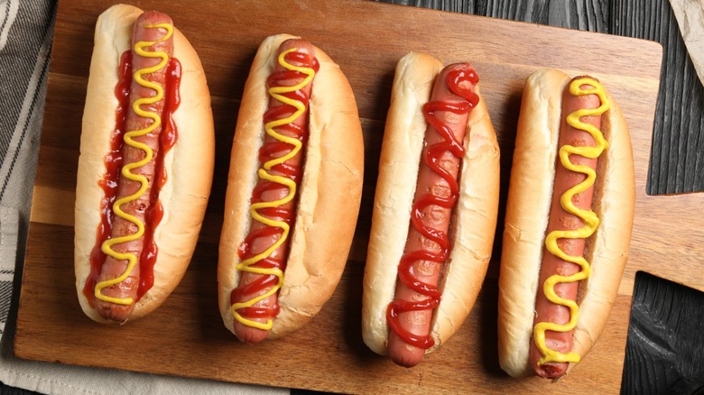 Hot dogs in buns on serving board topped with mustard and ketchup